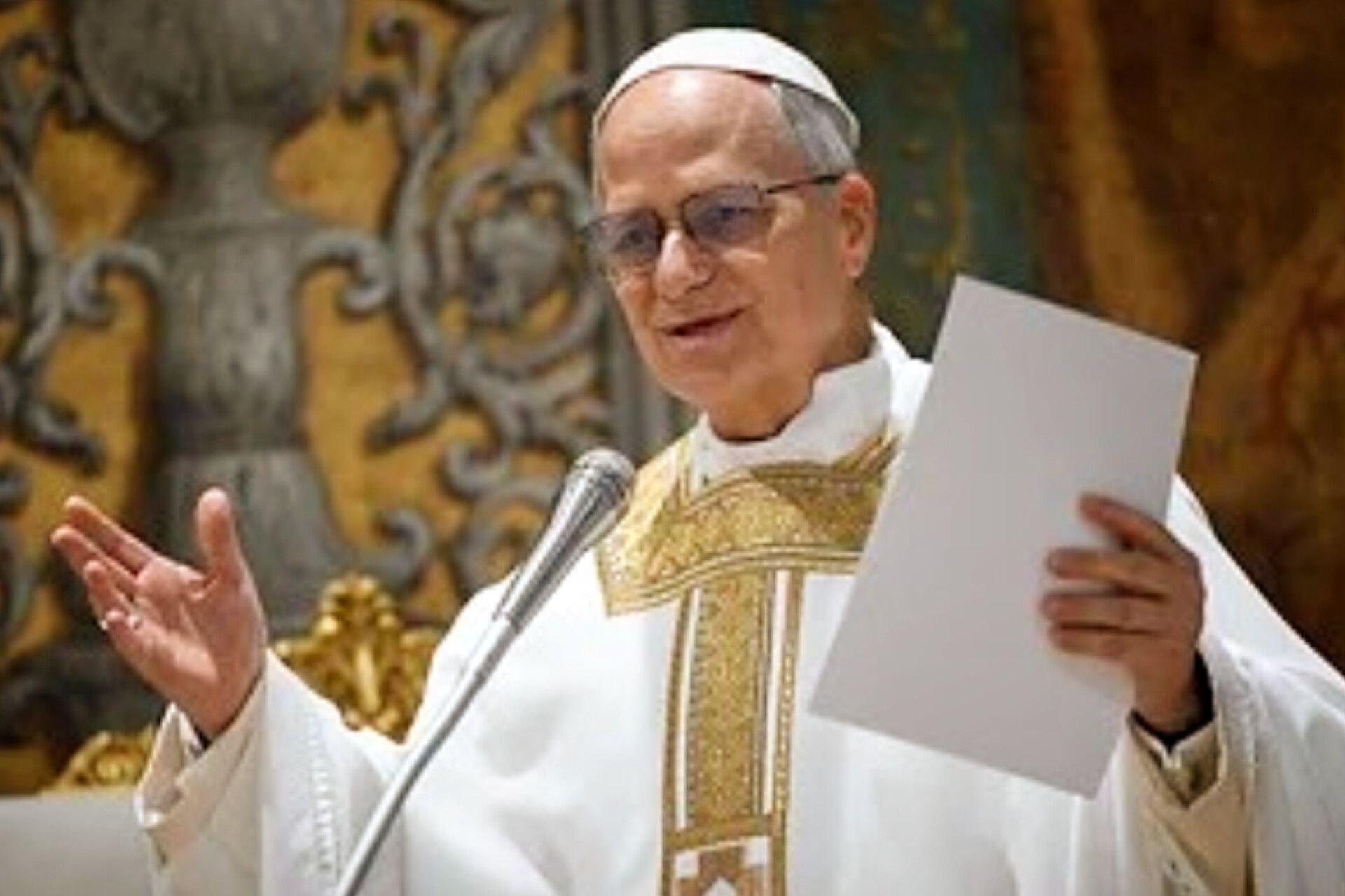 El papa León XIV habla ante un micrófono y sostiene unas hojas durante una celebración.